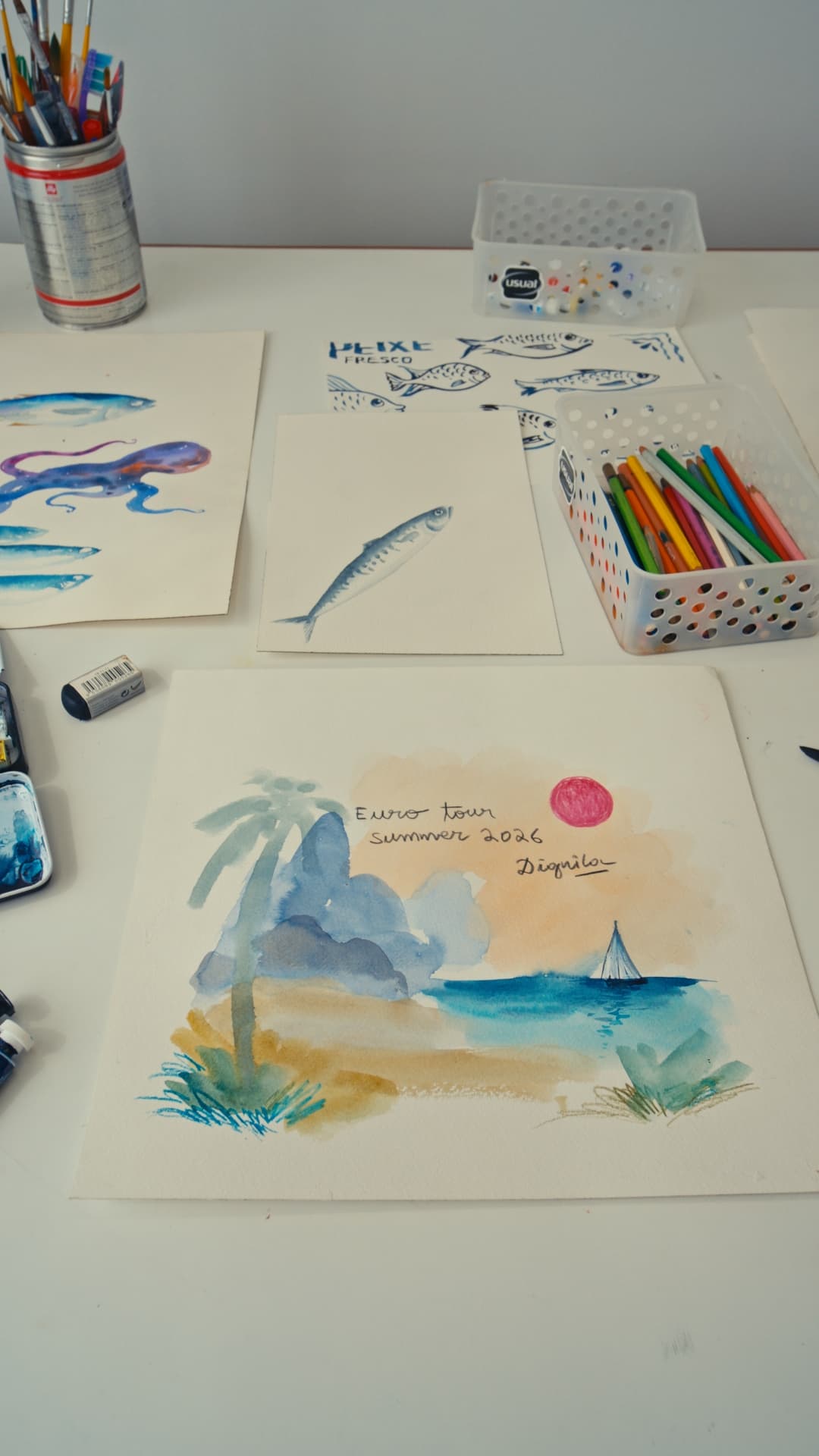 Mesa de trabalho com aquarelas de peixes e de mar