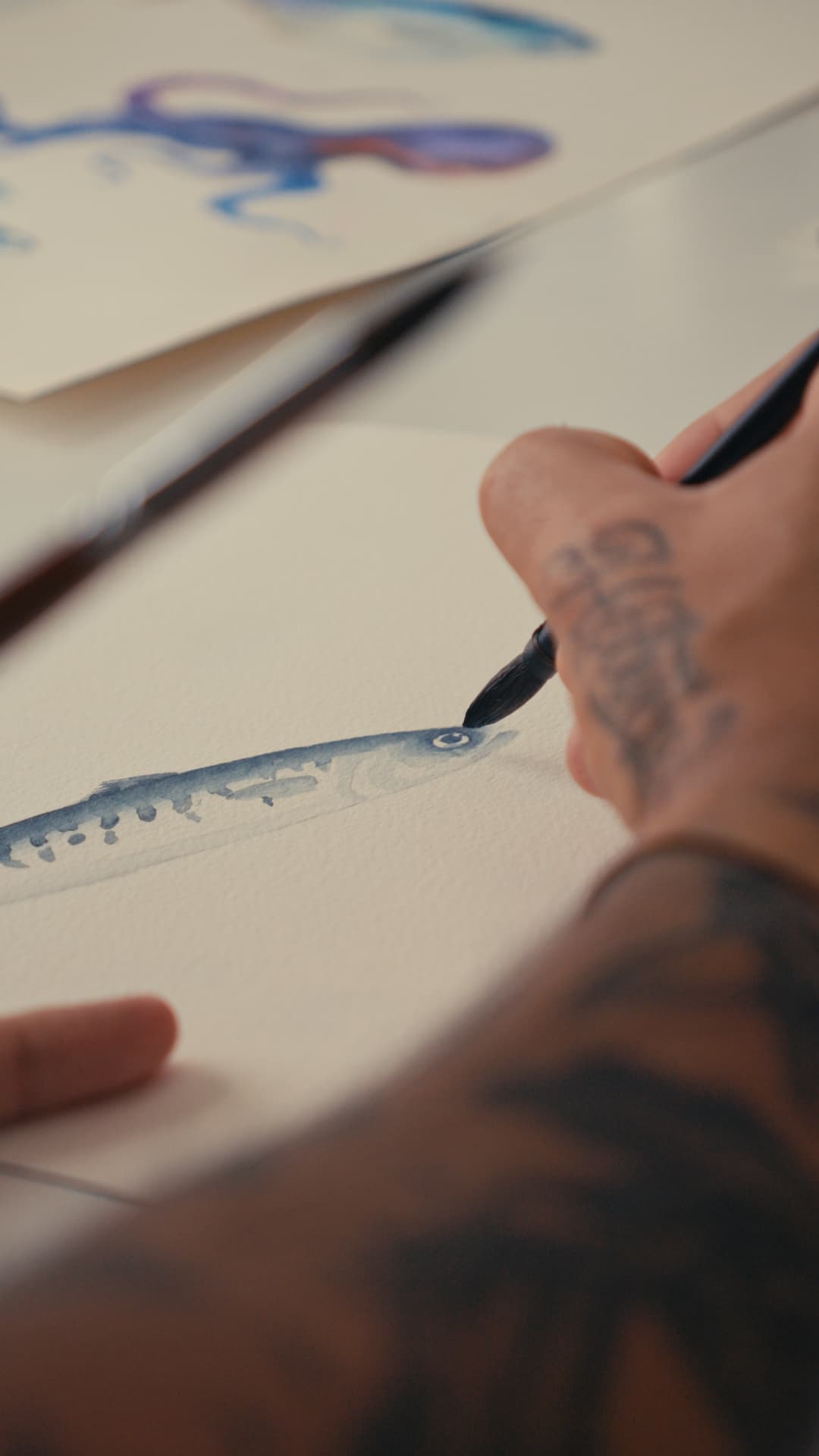 Pincel a desenhar uma sardinha em aquarela azul