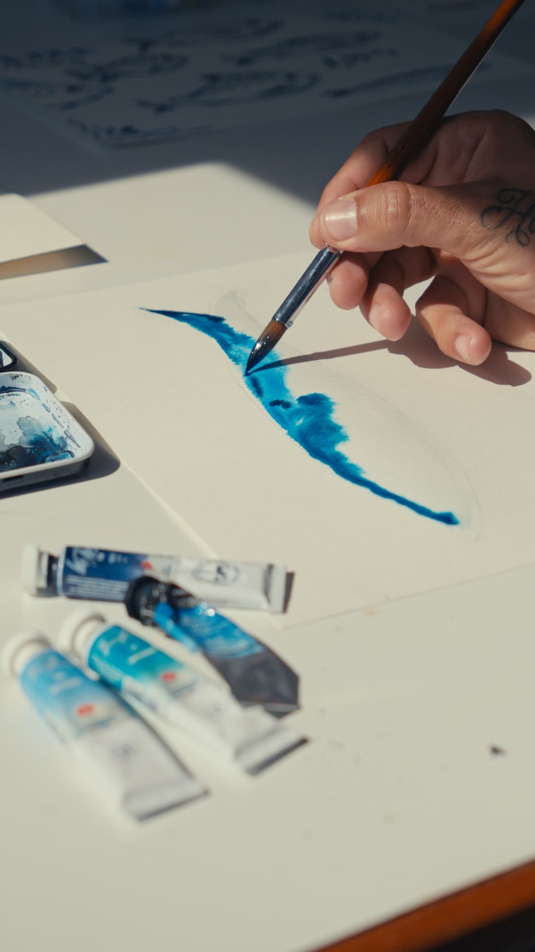 Pincel a puxar um traço de tinta azul sobre papel de aquarela